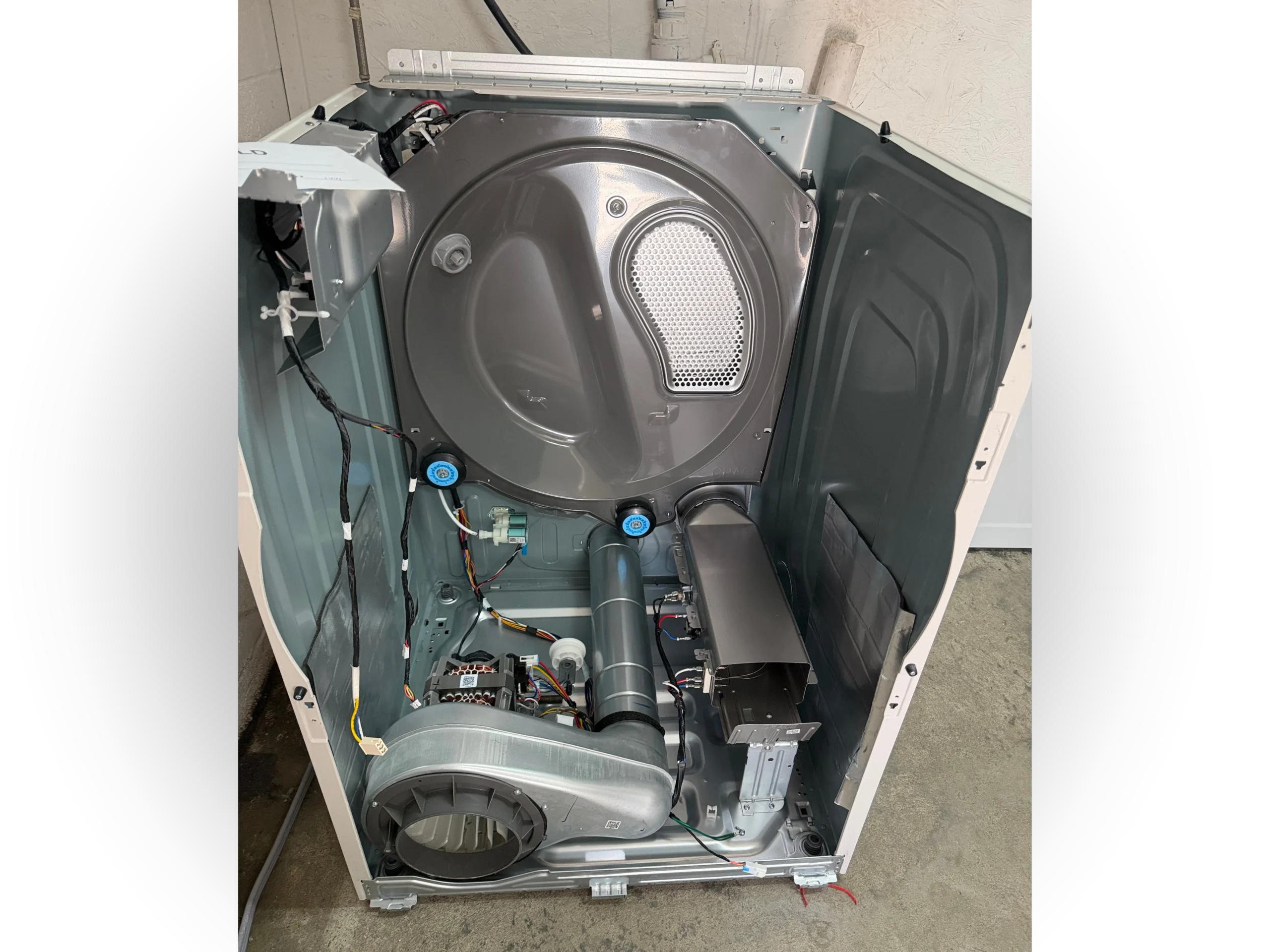 Interior view of a Samsung heat pump dryer with the front panel removed, showing the drum, centrifugal blower fan, heat pump evaporator and condenser units, control board, solenoid valves, and wiring harness.