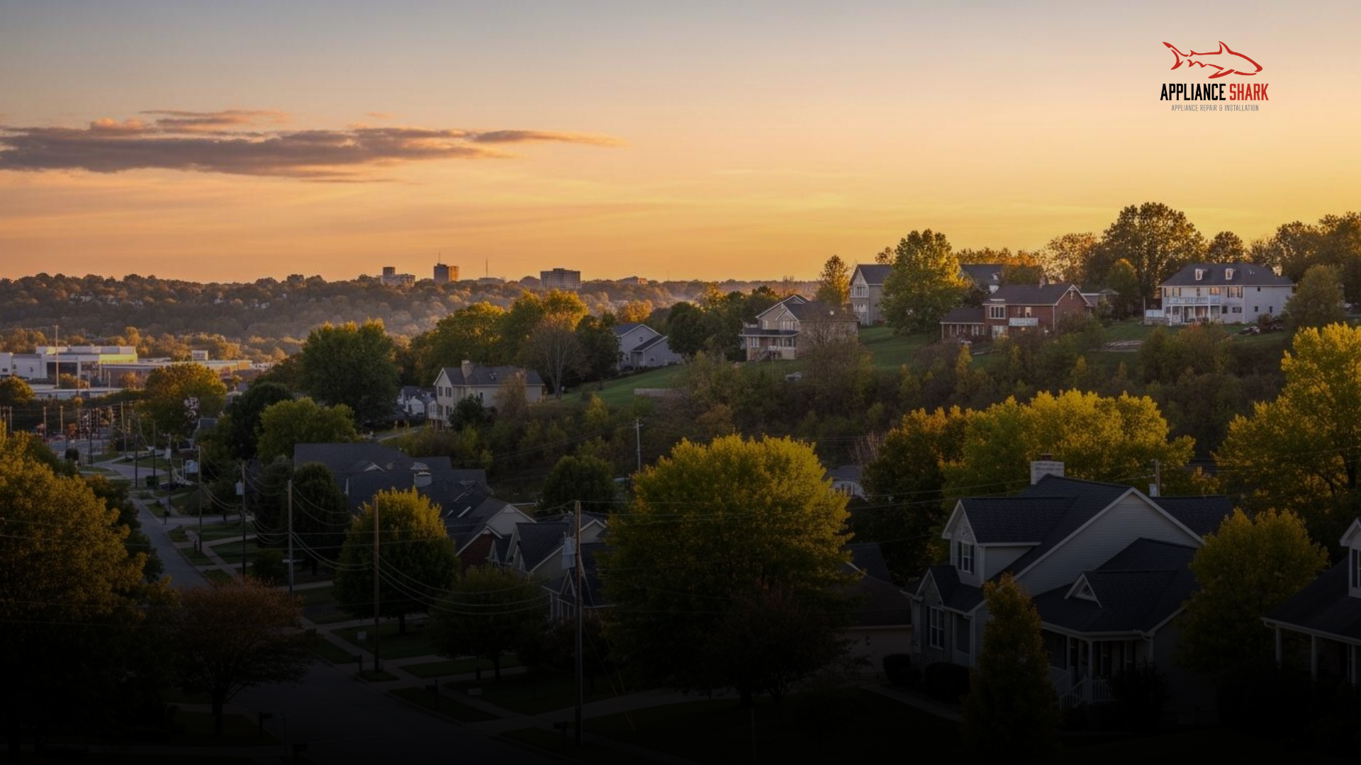 Aerial view of a tree-lined residential neighborhood in Gladstone, Missouri, at sunset with the city skyline in the distance