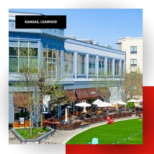 Outdoor dining and retail area with blue and white storefronts and green lawn in Leawood, Kansas